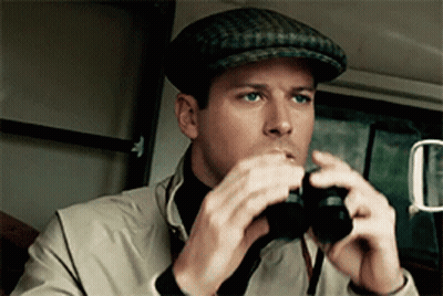 A Man Wearing A Hat Looks Through Binoculars In A Car GIF