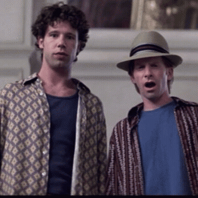 A Man Wearing A Hat Stands Next To Another Man GIF
