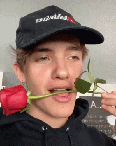 A Man Wearing A Hat That Says ' A. ' On It Is Holding A Rose In His Mouth GIF