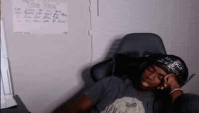 A Man Wearing A Hat That Says " All Is Calm " Is Sleeping In A Chair GIF