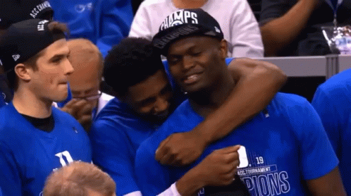 A Man Wearing A Hat That Says Champions On It Is Hugging Another Man GIF