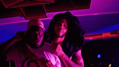 A Man Wearing A Hat That Says Gucci On It Stands Next To Another Man GIF