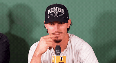 A Man Wearing A Hat That Says Kings Is Sitting In Front Of A Microphone GIF