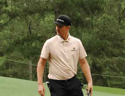 A Man Wearing A Hat That Says Stanley Is Walking On A Golf Course GIF