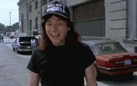 A Man Wearing A Hat That Says `` Wayne 'S World '' Is Laughing On A Street . GIF