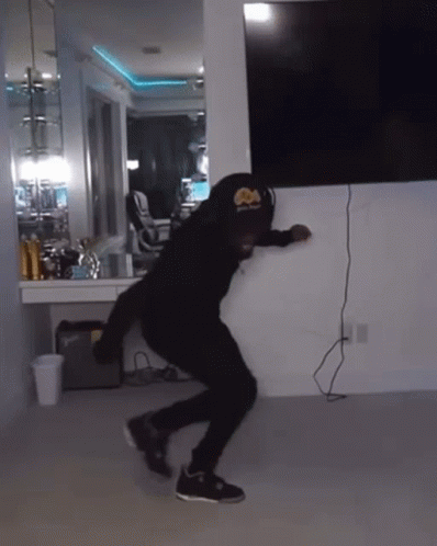 A Man Wearing A Hat With A Crown On It Is Dancing In A Room GIF