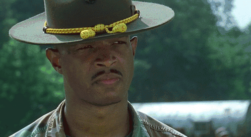 A Man Wearing A Hat With A Yellow Rope Around The Brim GIF