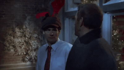 A Man Wearing A Hat With Reindeer Antlers Is Talking To Another Man GIF