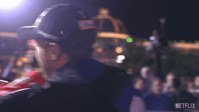 A Man Wearing A Hat With The Letter B On It Is Standing In Front Of A Crowd And A Sign That Says Netflix GIF