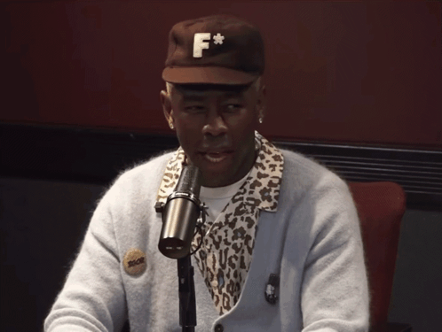 A Man Wearing A Hat With The Letter F On It Is Sitting In Front Of A Microphone GIF