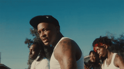 A Man Wearing A Hat With The Letter T On It Stands In Front Of A Group Of Men GIF
