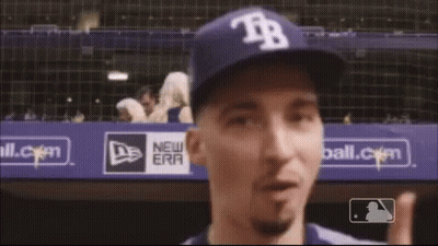 A Man Wearing A Hat With The Letter Tr On It Points Up GIF