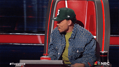 A Man Wearing A Hat With The Number 3 On It Sits In A Chair GIF