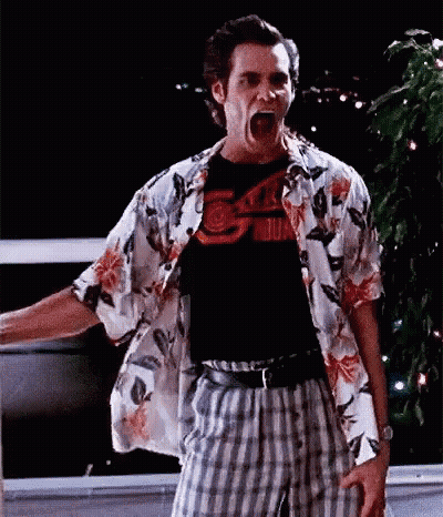 A Man Wearing A Hawaiian Shirt And Plaid Pants Is Standing In Front Of A Window With His Mouth Open . GIF