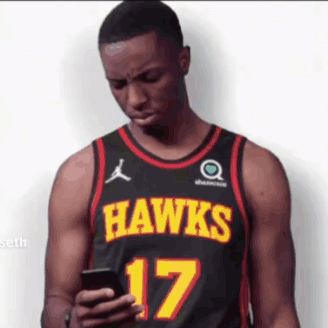A Man Wearing A Hawks Jersey Looks At His Phone GIF