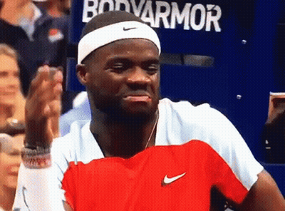 A Man Wearing A Headband And A Red And White Nike Shirt Stands In Front Of A Sign That Says Bodyarmor GIF