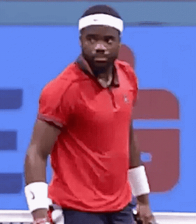 A Man Wearing A Headband And A Red Shirt Is Playing Tennis On A Tennis Court . GIF