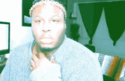 A Man Wearing A Headband And A Sweater Is Making A Funny Face While Sitting On A Couch . GIF