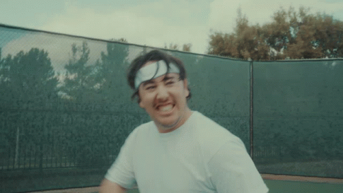 A Man Wearing A Headband And A White Shirt Is Playing Tennis GIF