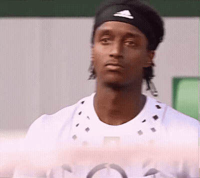 A Man Wearing A Headband And A White Shirt Looks At The Camera . GIF