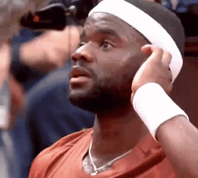 A Man Wearing A Headband And A Wristband Adjusts His Hair . GIF