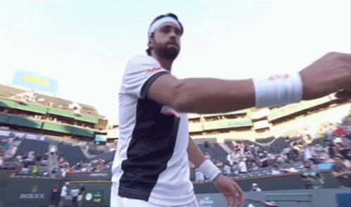 A Man Wearing A Headband And A Wristband Is Standing On A Tennis Court With A Rolex Sign In The Background GIF