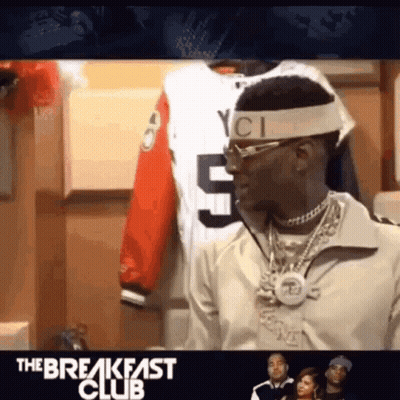 A Man Wearing A Headband And Sunglasses Is Standing In Front Of A Display Of Shirts . GIF