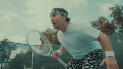 A Man Wearing A Headband Holds A Tennis Racquet On A Tennis Court GIF