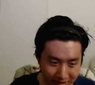 A Man Wearing A Headband Is Looking At The Camera . GIF