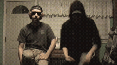 A Man Wearing A Headband That Says Budweiser Is Sitting Next To Another Man GIF
