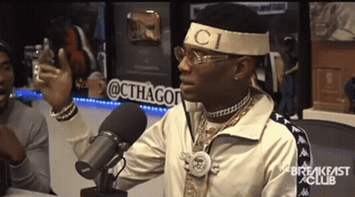 A Man Wearing A Headband That Says Gucci Is Talking Into A Microphone GIF