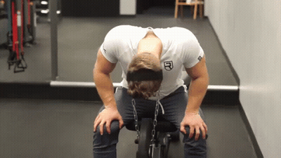 A Man Wearing A Headband With The Letter R On It Sits On A Bench In A Gym GIF