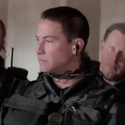 A Man Wearing A Headset And Ear Buds Is Standing In A Room . GIF