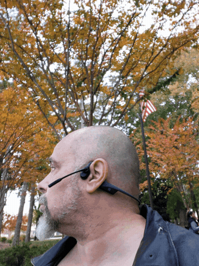 A Man Wearing A Headset Is Standing In Front Of Trees GIF