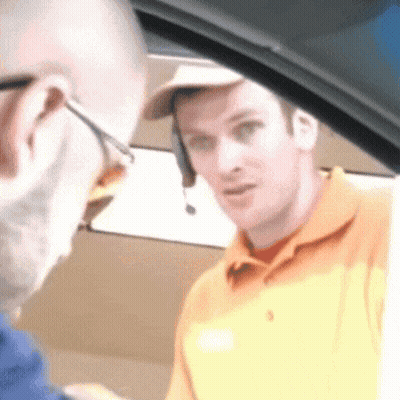 A Man Wearing A Headset Is Talking To Another Man While Sitting In A Car . GIF