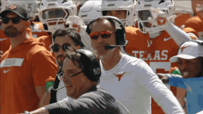 A Man Wearing A Headset Stands In Front Of A Texas Football Team GIF