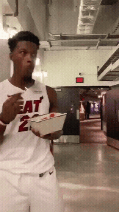 A Man Wearing A Heat Jersey Is Eating Something GIF
