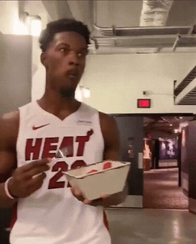 A Man Wearing A Heat Jersey Is Holding A Container Of Food GIF