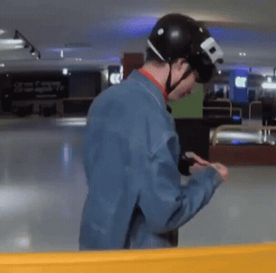 A Man Wearing A Helmet And A Blue Jacket Is Looking At His Cell Phone . GIF