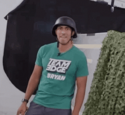 A Man Wearing A Helmet And A Green Team Edge T-Shirt . GIF
