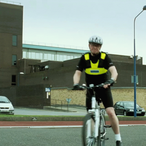 A Man Wearing A Helmet And A Vest That Says Police On It Is Riding A Bike GIF