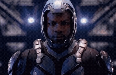 A Man Wearing A Helmet And Armor Is Standing In A Dark Room . GIF