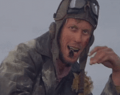 A Man Wearing A Helmet And Goggles Is Eating A Piece Of Bread . GIF