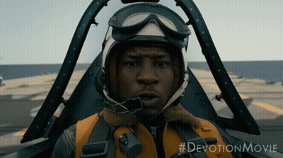 A Man Wearing A Helmet And Goggles Is Sitting In A Plane With The #Devotionmovie Written Below Him GIF