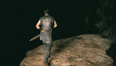 A Man Wearing A Helmet And Holding A Sword Is Walking On A Rock In The Dark GIF