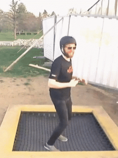 A Man Wearing A Helmet And Sunglasses Is Standing On A Trampoline GIF