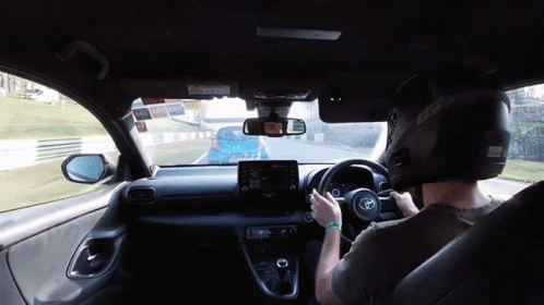 A Man Wearing A Helmet Is Driving A Car With The Word Toyota On The Steering Wheel GIF