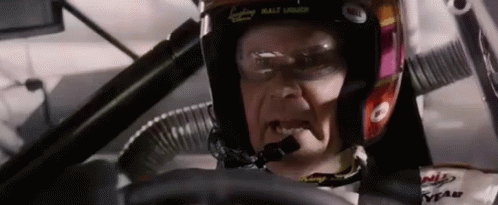 A Man Wearing A Helmet Is Driving A Race Car . GIF