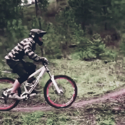 A Man Wearing A Helmet Is Riding A Bike On A Dirt Path GIF