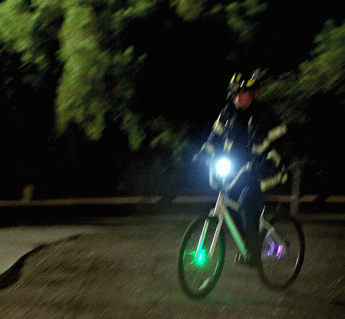 A Man Wearing A Helmet Is Riding A Bike With A Light On The Front Wheel GIF
